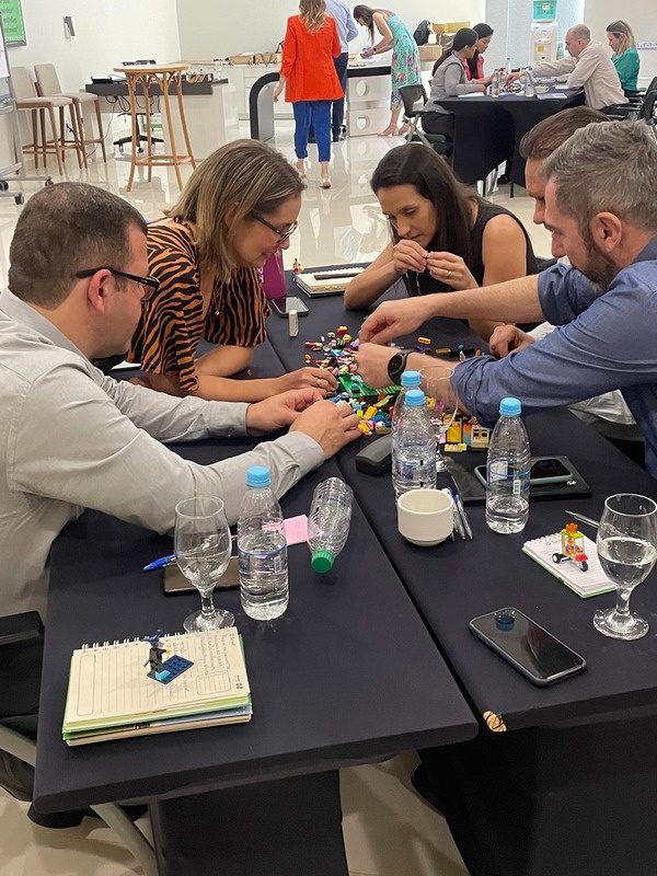 Grupo de profissionais construindo com peças de montar durante uma dinâmica de teambuilding.